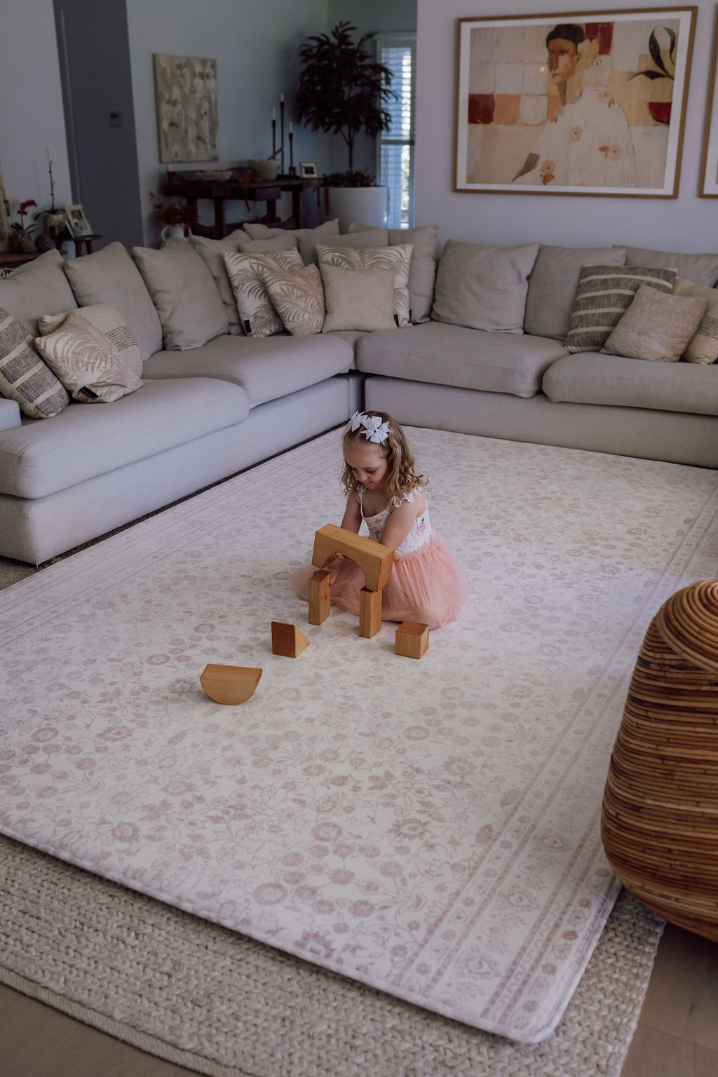 Young girl playing with wooden blocks on a patterned little wiwa lavish rug in a living room.